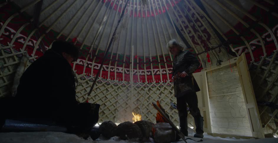Two men around a fire in a large tent