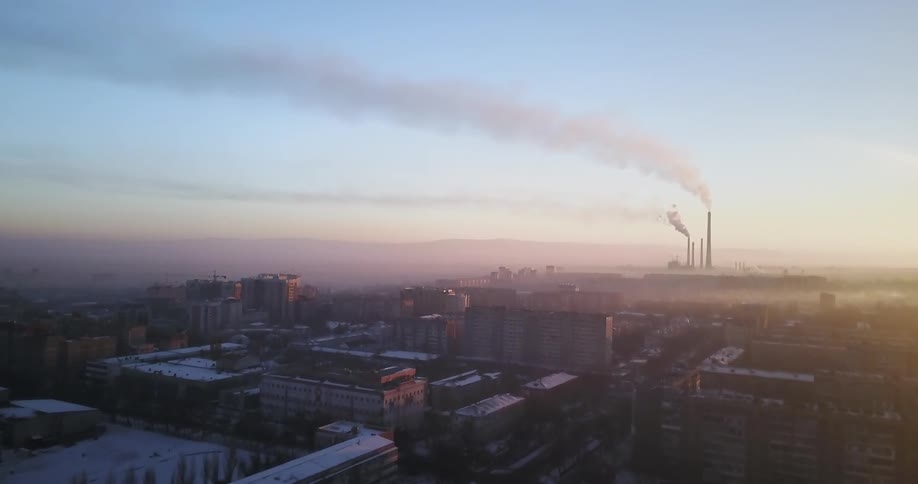 Smoke rises from a factory at sunset
