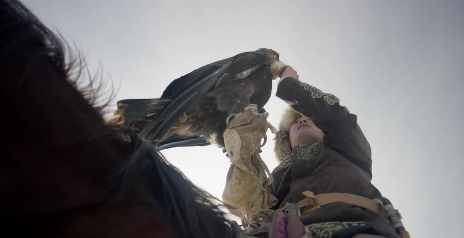 A man rides a horse with a hunting eagle