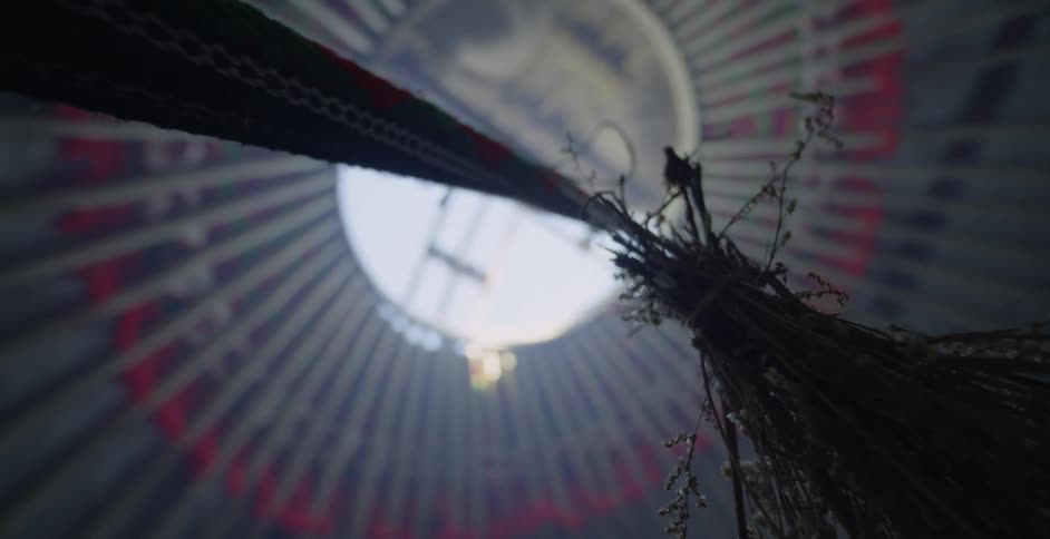 Grass hang from a rope near the top of a yurt opening