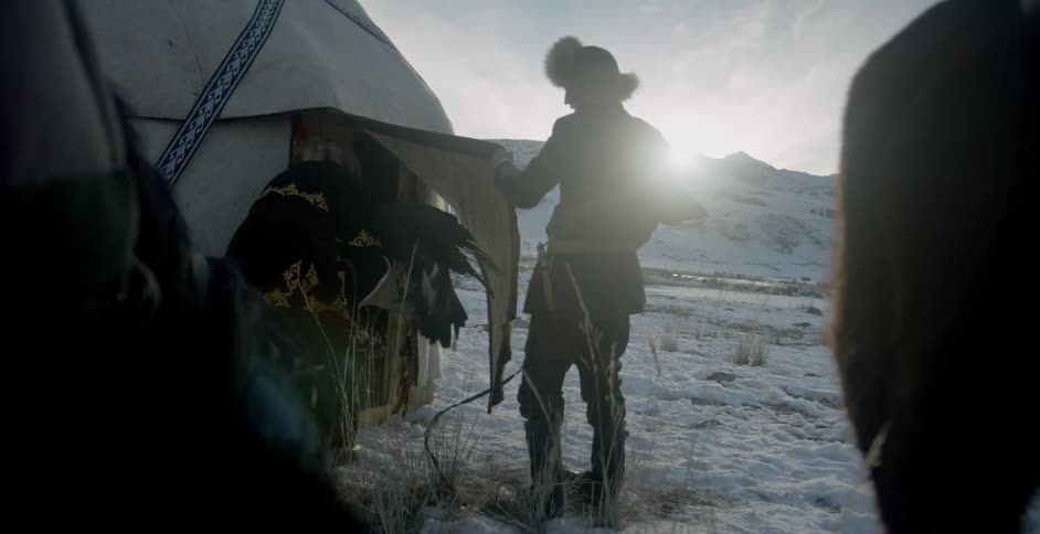 Two men enter a tent holding eagles