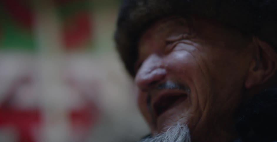 An elderly bearded toothless man laughs and smiles