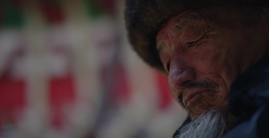 A fire shines on an elderly man's face