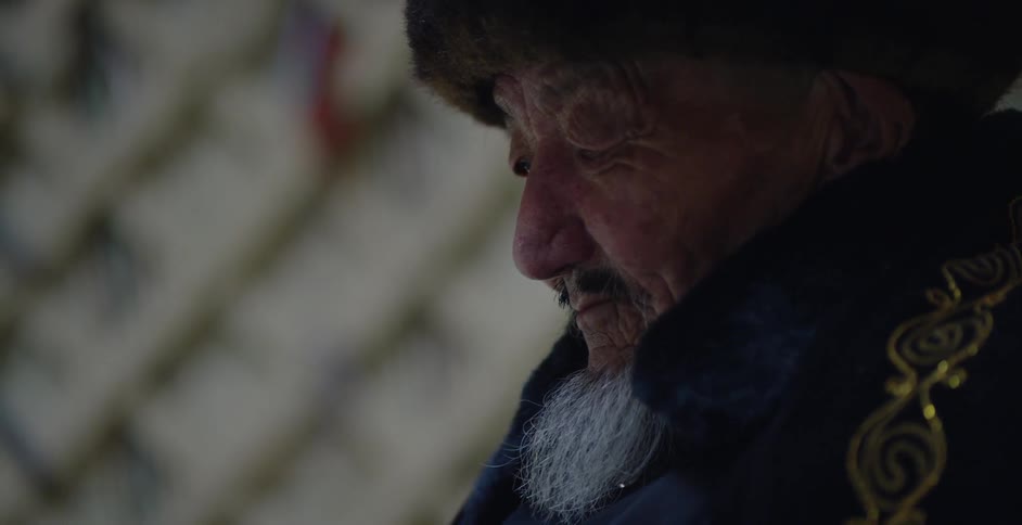 An elderly man leans back looking down