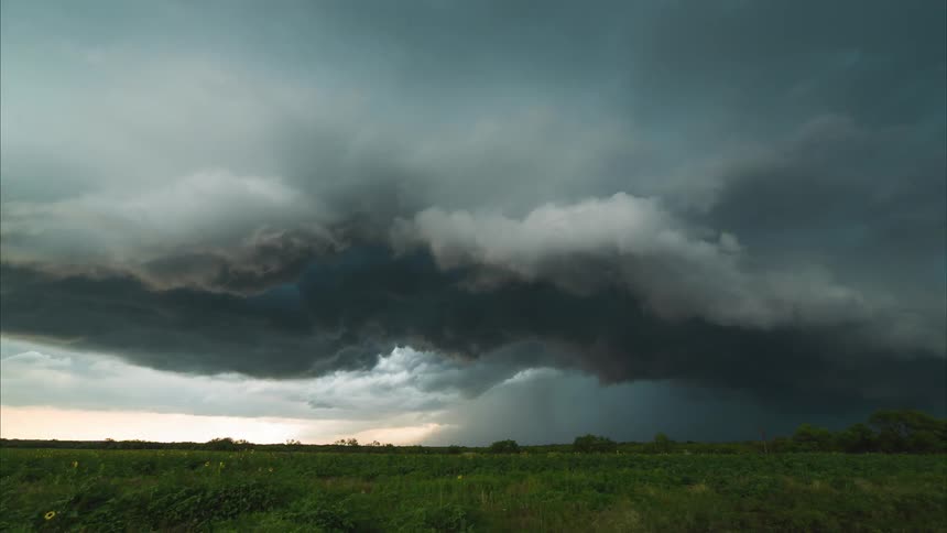 Timelapse view of large, dark clouds rolling in over a field