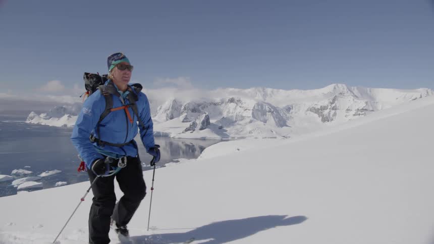 A skier hikes up a snowy mountainside
