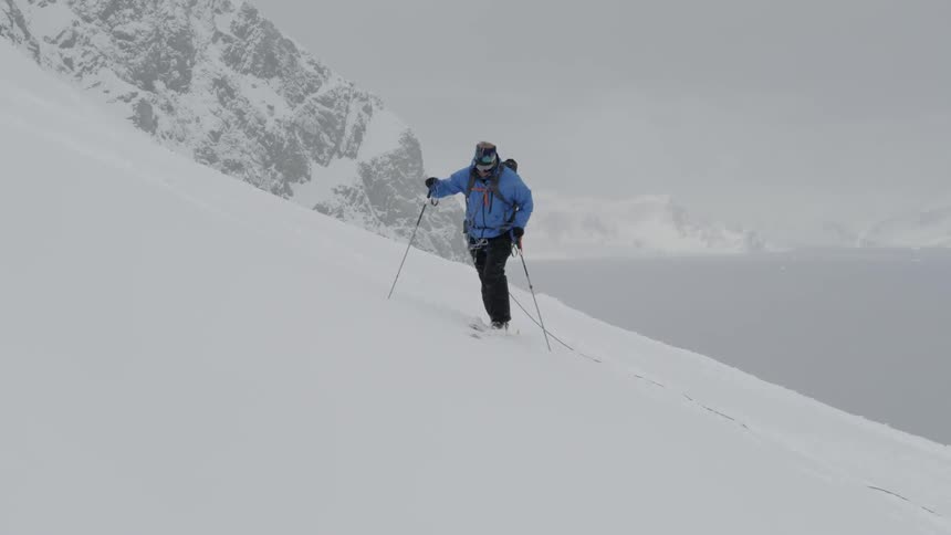 A skier hikes up a snowy mountainside