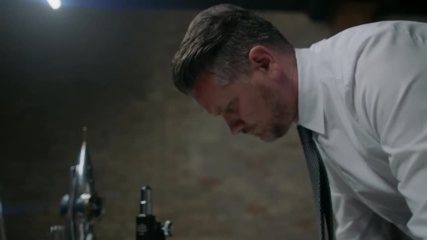 A man bends over a table and makes notes