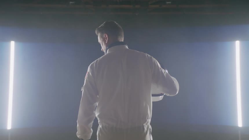 A man holding an astronaut helmet looks to the side