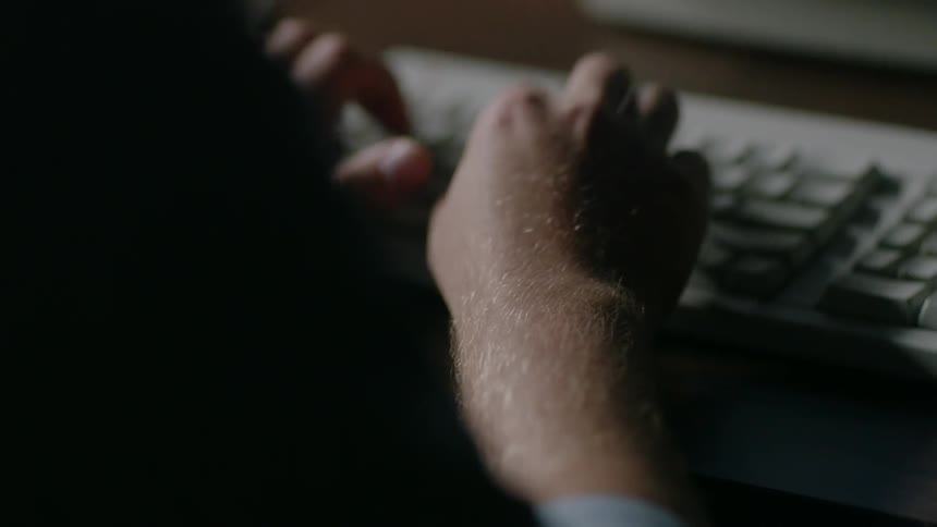 A man types on a computer keyboard