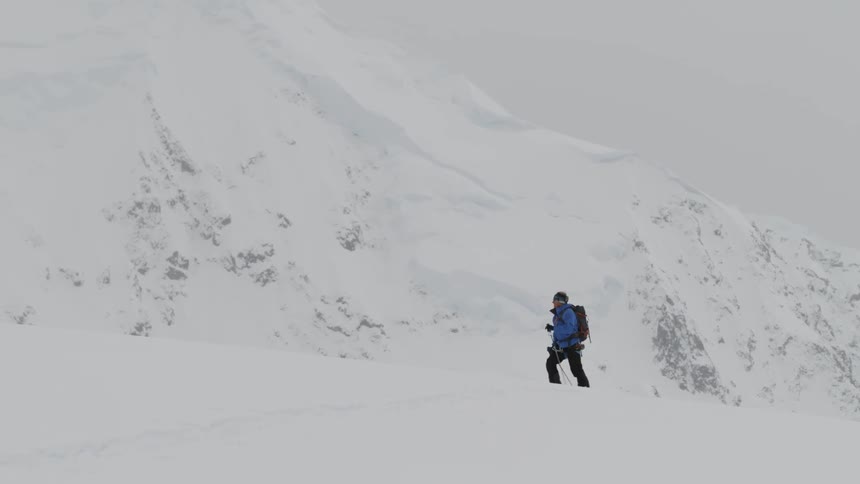 Person hikes on snowy terrain using poles