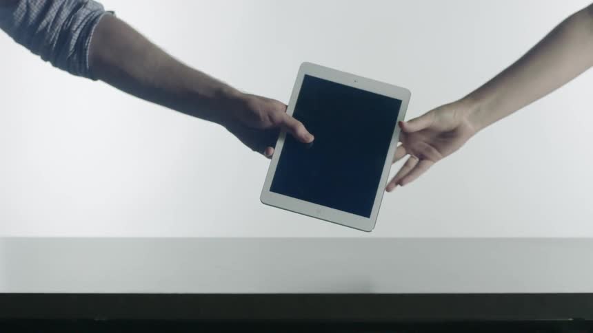 A person hands a tablet over to someone