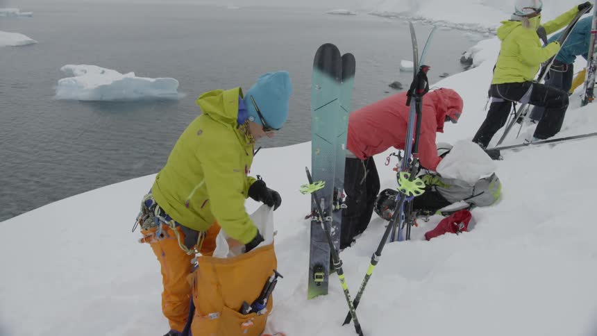 A group of skiers is preparing their gear as they stand outside on a snowy day