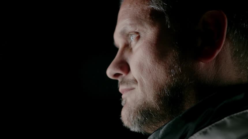 A man slowly looks up towards a light