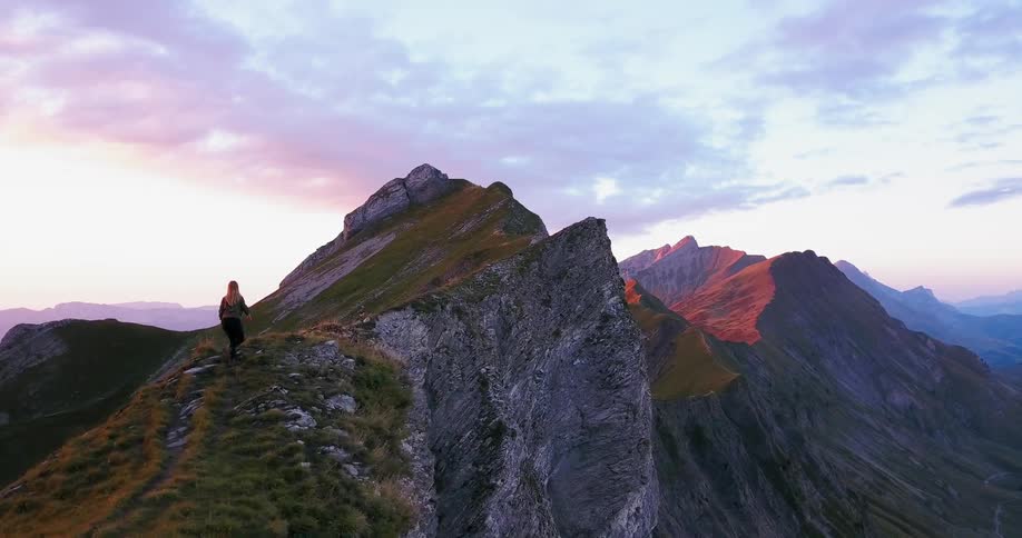 Person hikes up a large mossy rock at sunrise