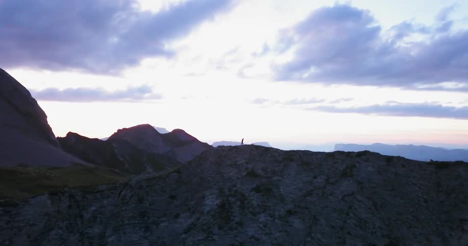 A person is slowly walking over the mountain ahead