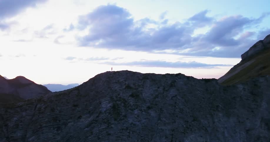 A hiker climbs in a mountain ridge at sunset