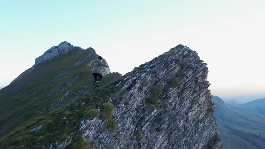 A hiker climbs up a mountain peak