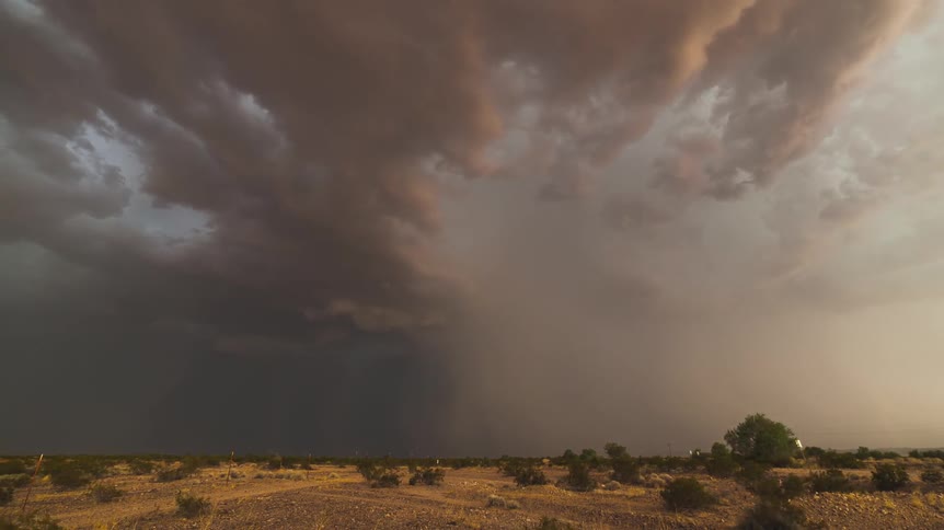 View of a field as a large storm forms up ahead
