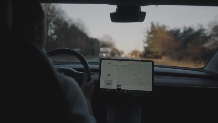 Person driving a car while looking at a map on a screen