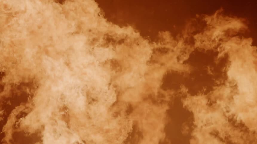 A large fire burns outside at night