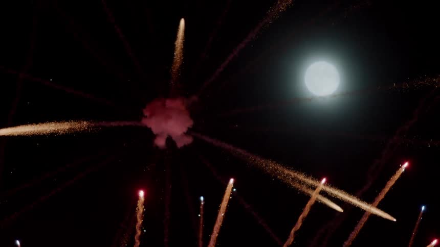 Fireworks explode in the night sky next to the moon