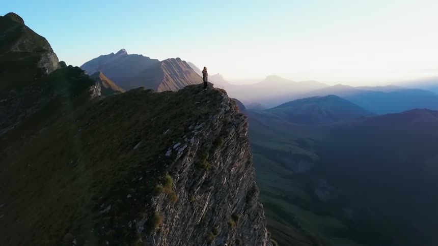 A hiker stands on a mountain peak