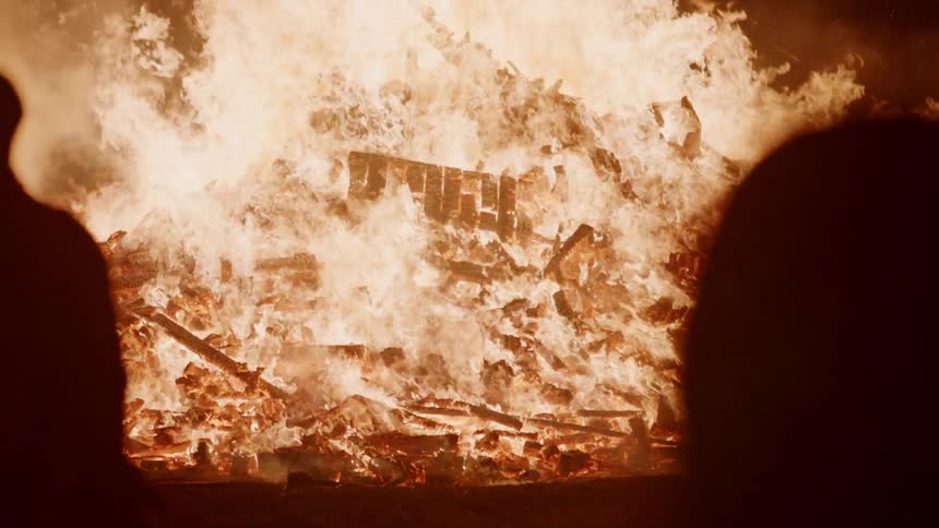 A large bonfire burns at night