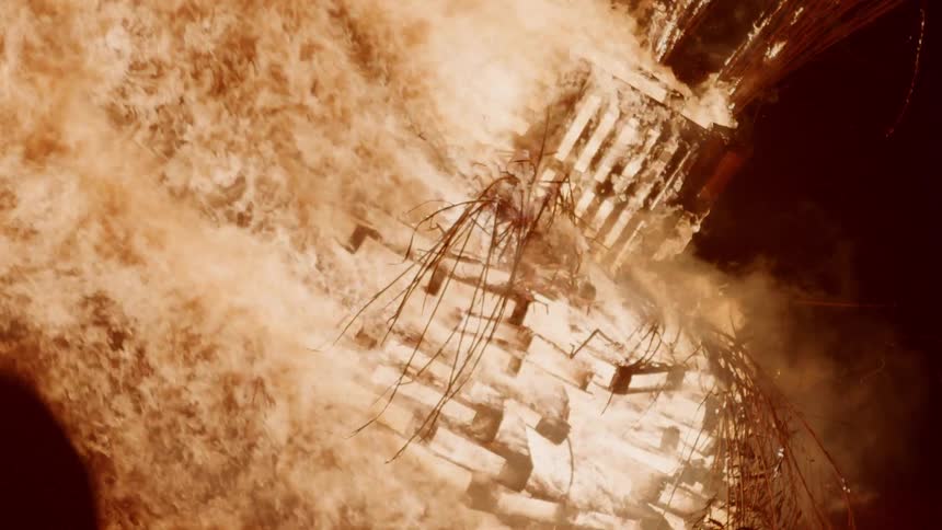 Fire blazes brightly and burns through a wooden structure