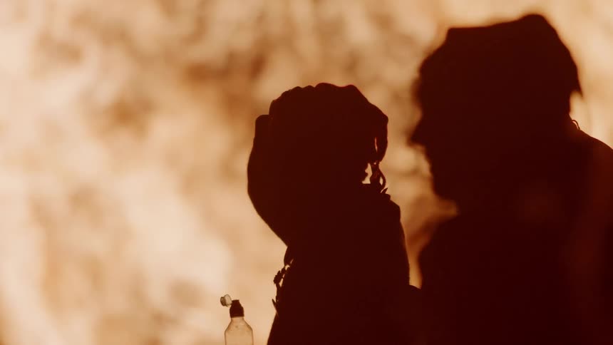 People stand outside as fire blazes brightly