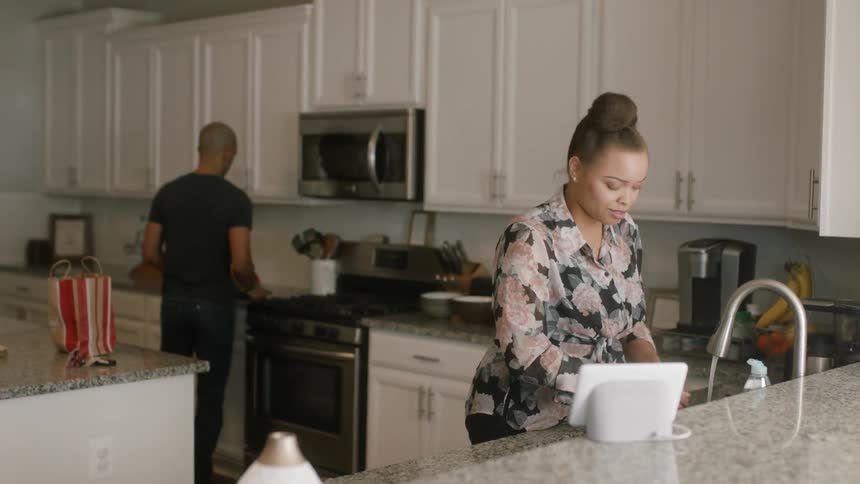 Two people talk as they use the kitchen