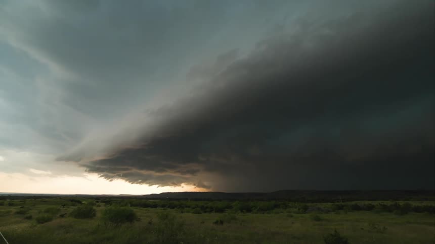 A big storm forms over a grassy plain