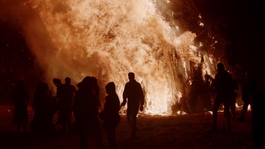 People stand outside as fire blazes brightly