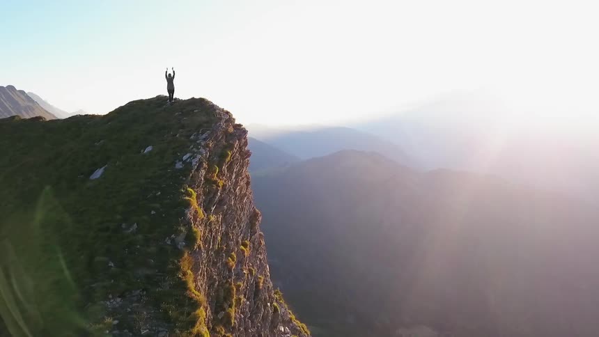 A person stretches on a mountain peak at sunrise