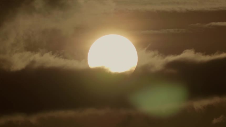 The sun sets behind the thick clouds