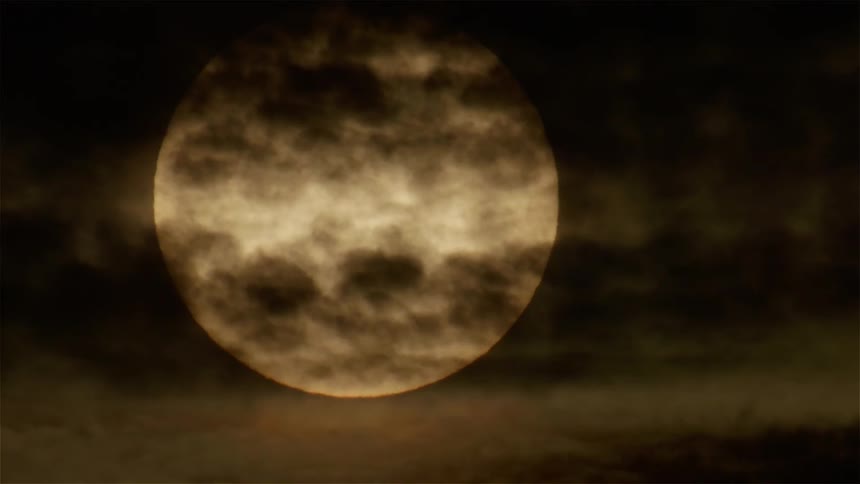 Clouds passing over the large round sun