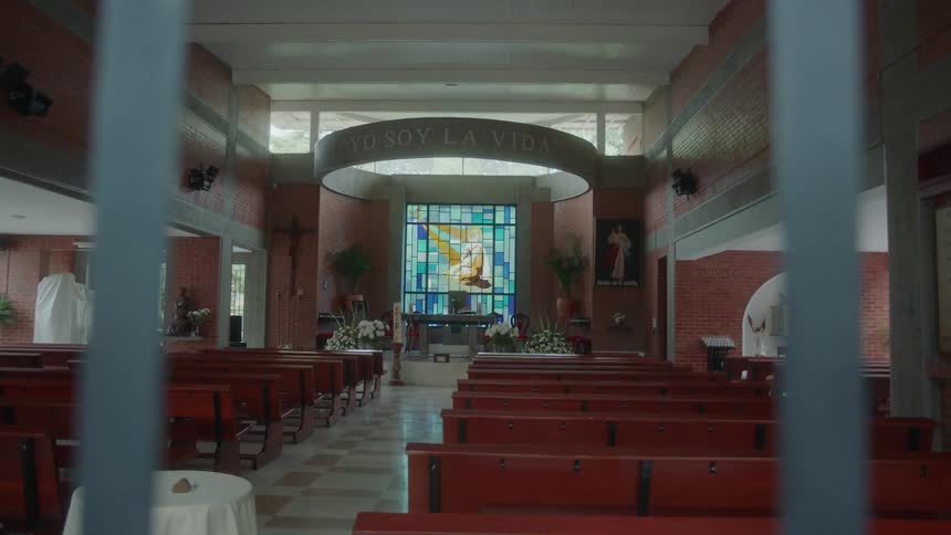 The church is empty with stained glass showing in sun