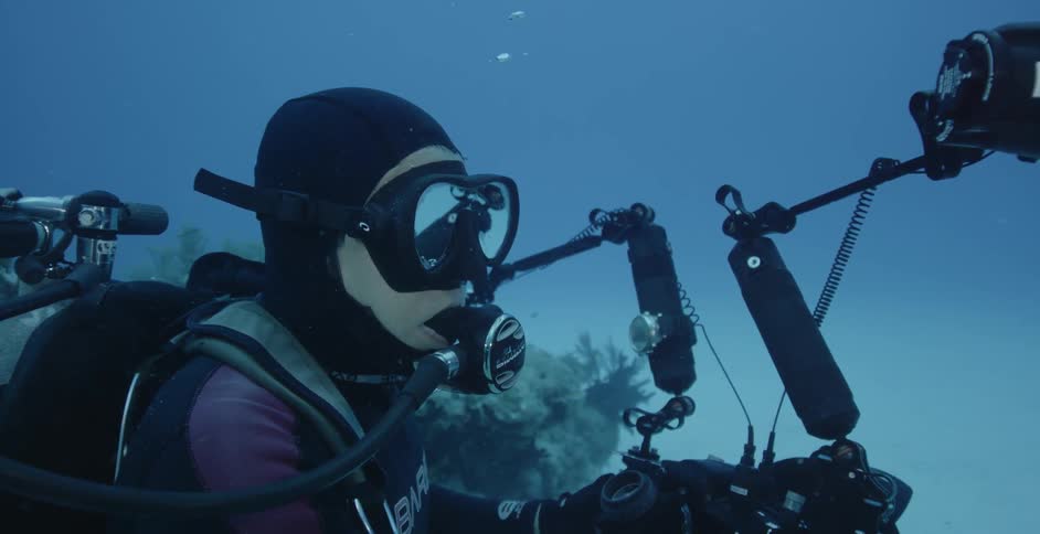 Underwater diver surrounded by equipment blows out bubbles