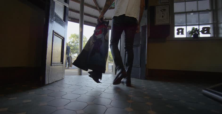 A man carrying a jacket walks through a building to the exit