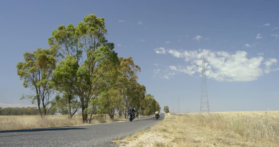 Motorcycles drive down a country road