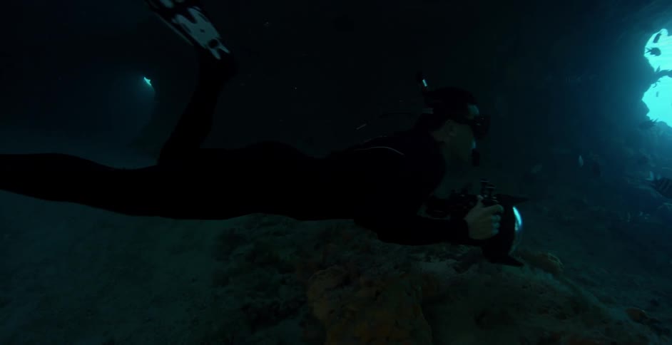 Diver swims in dark water