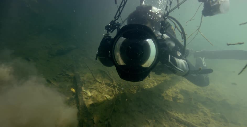 A diver takes photographs while swimming