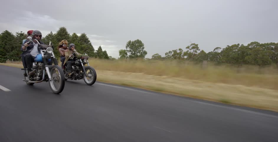 Two couples are riding motorcycles side by side