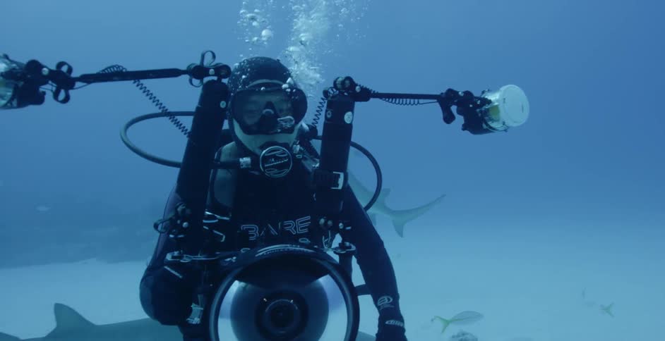 Diver holding camera blows out bubbles and waves