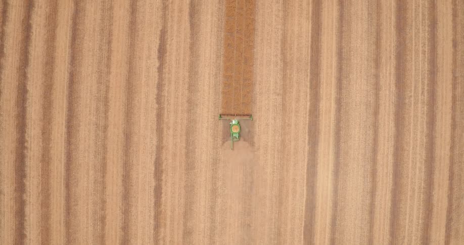A harvester is working a field on a farm during the day