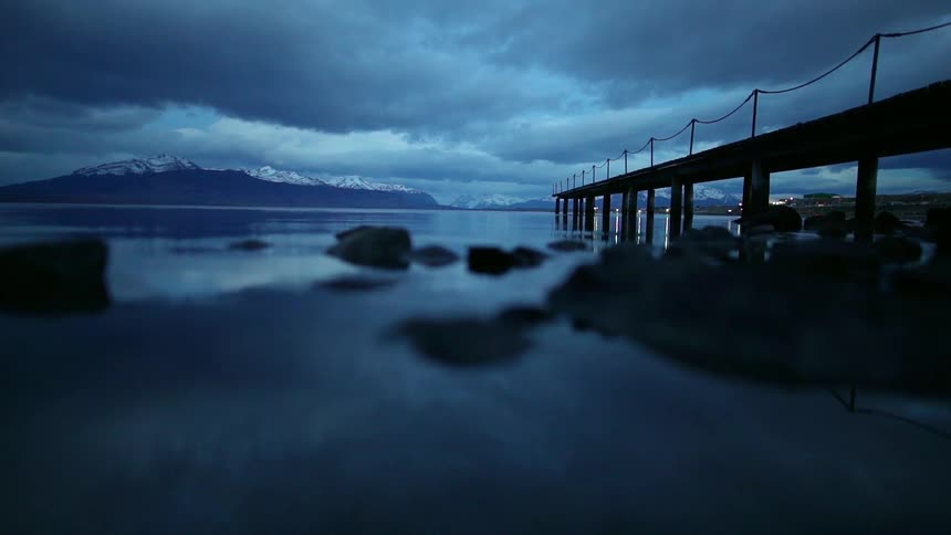 Storm clouds are hanging above a pier in a bay at dusk