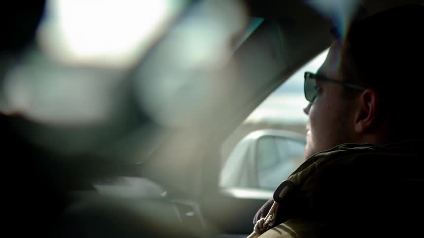 Two people ride in a car on a sunny day