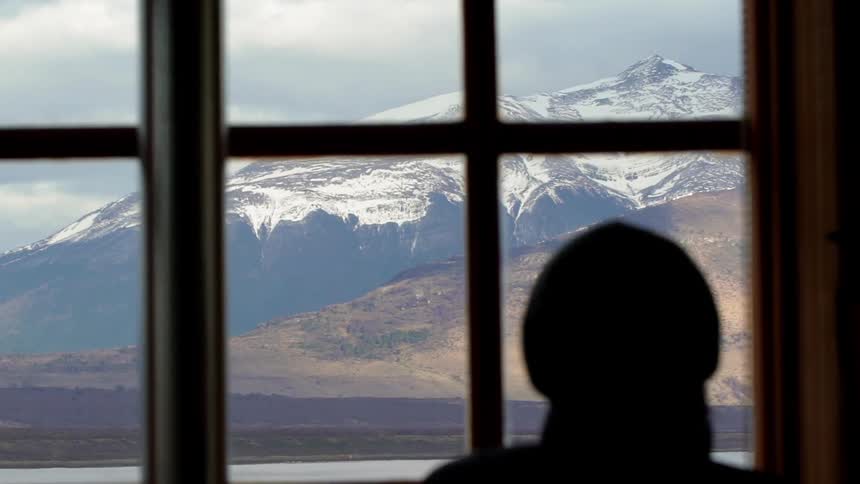 Person looks out the window at snowy mountains