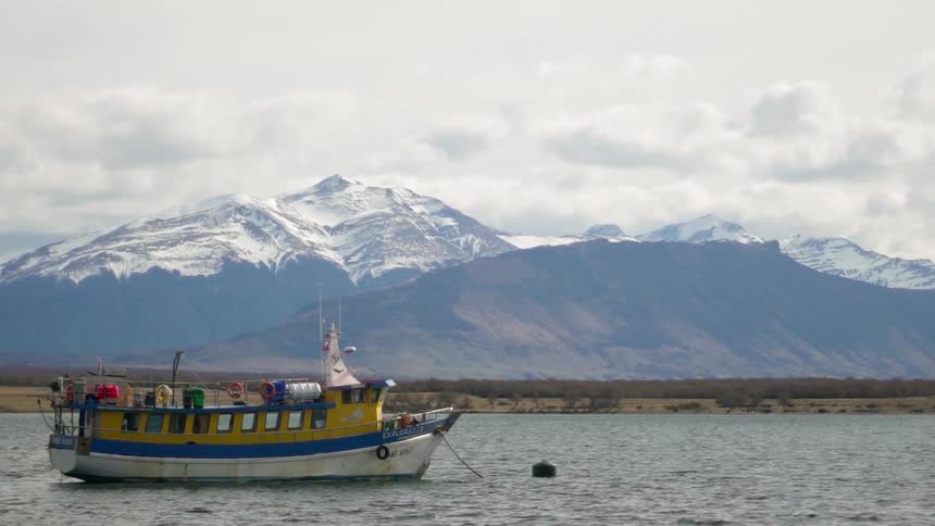 Boat floats in the lake next to the mountains