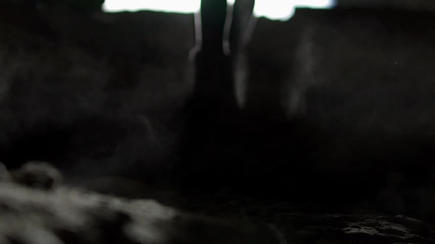 A woman is walking out of a cavern into daylight
